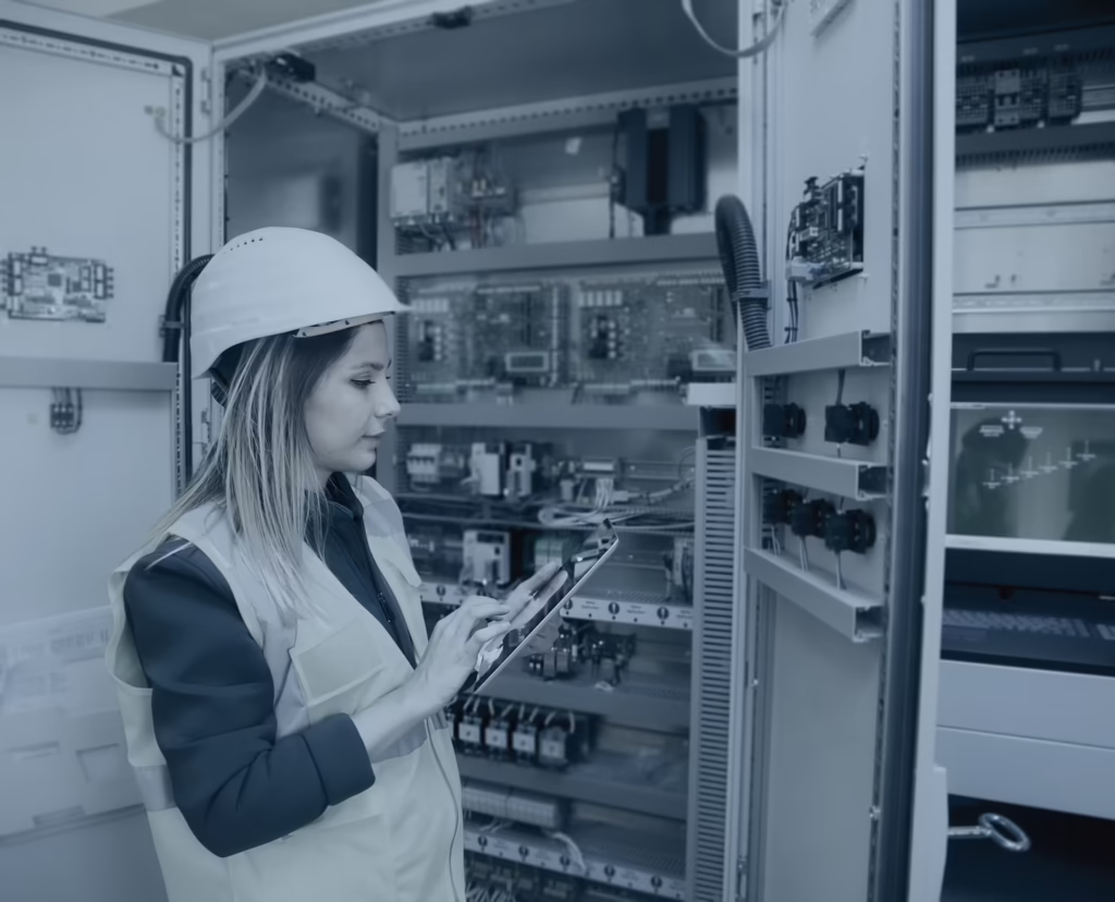 Engineer using a tablet at an electrical control cabinet